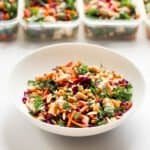 chicken salad in white bowl with chicken salads in containers in background