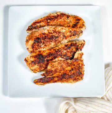 blackened chicken on white plate with yellow striped napkin