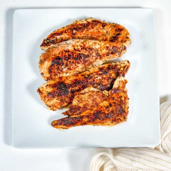 blackened chicken on white plate with yellow striped napkin