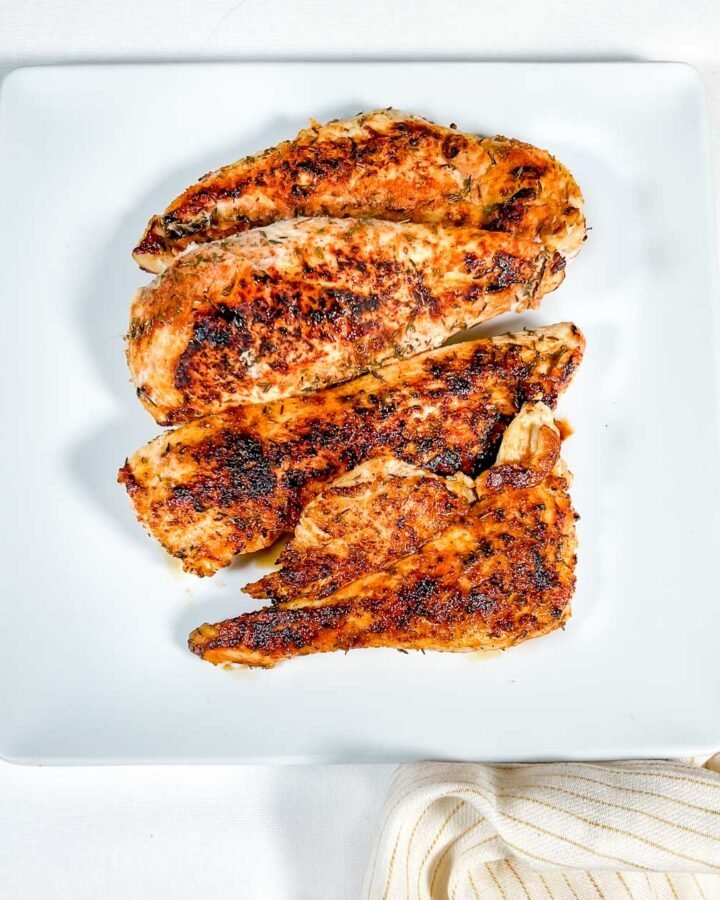 blackened chicken on white plate with yellow striped napkin