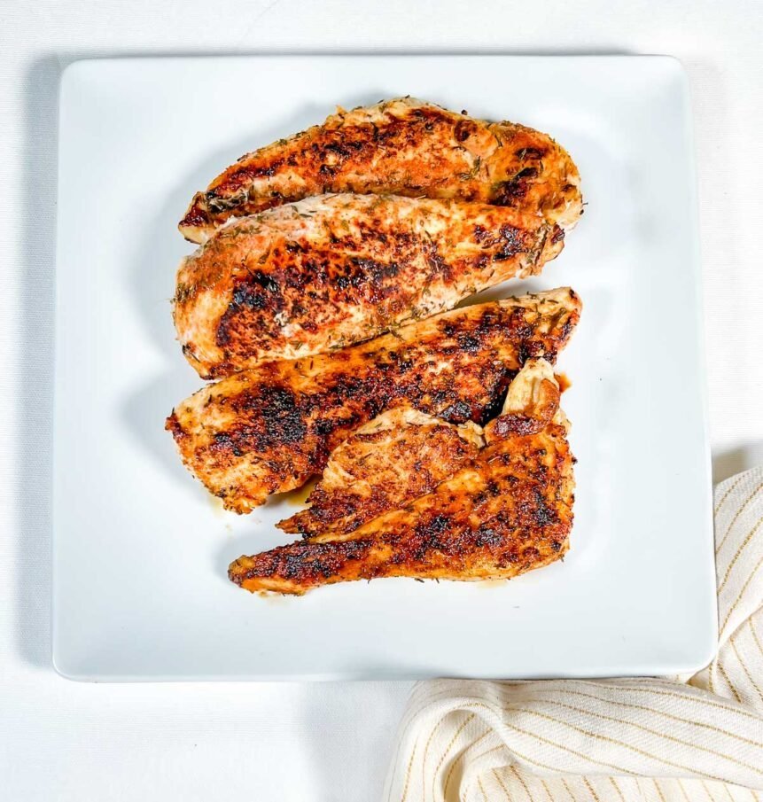 blackened chicken on white plate with yellow striped napkin