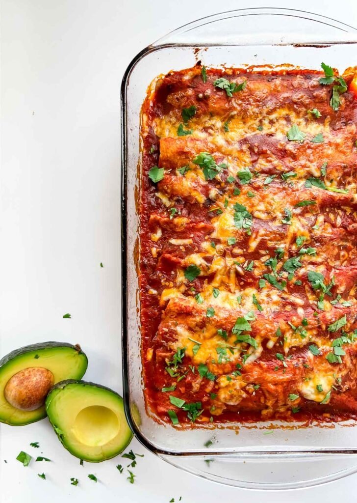 enchiladas in red sauce with cheese and avocados